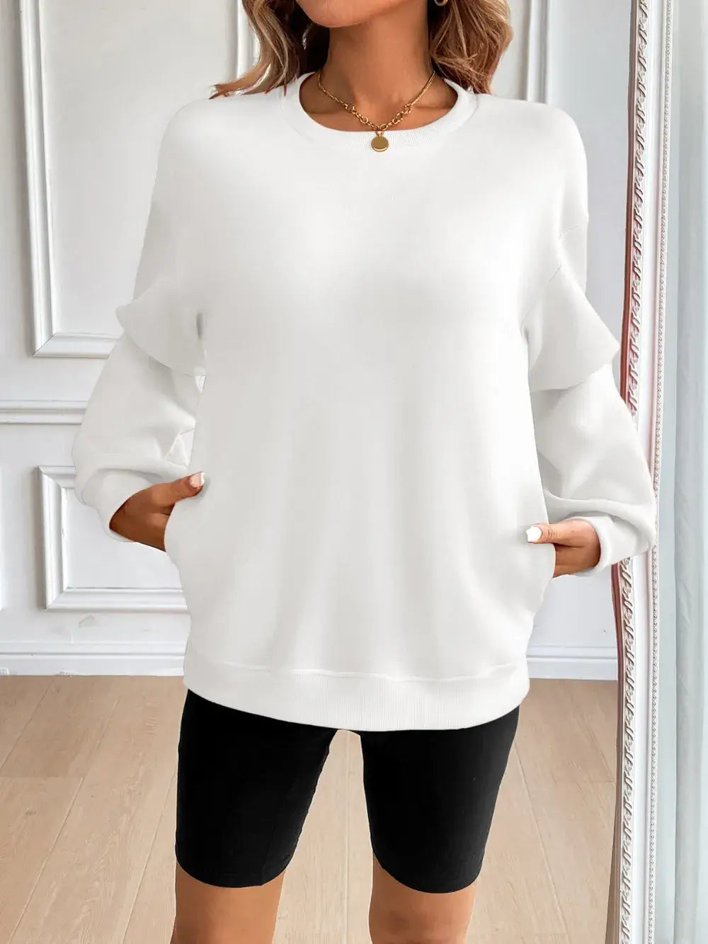 Ivy Lane Round Neck Long Sleeve Sweatshirt in white, featuring side pockets and a relaxed fit, styled with black shorts.