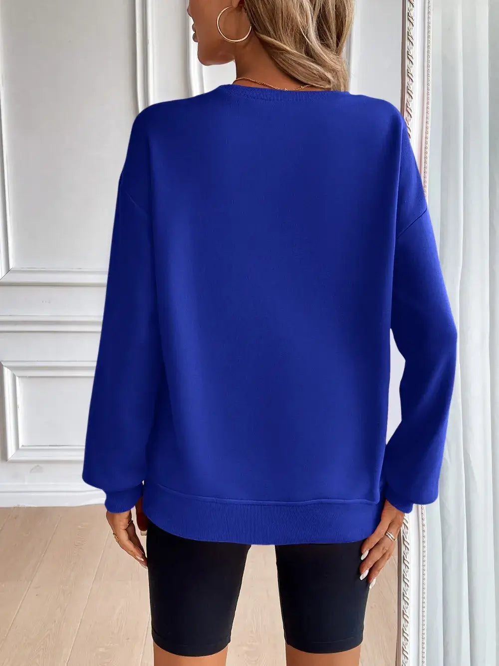 Back view of a woman wearing a blue Ivy Lane round neck long sleeve sweatshirt with casual style.