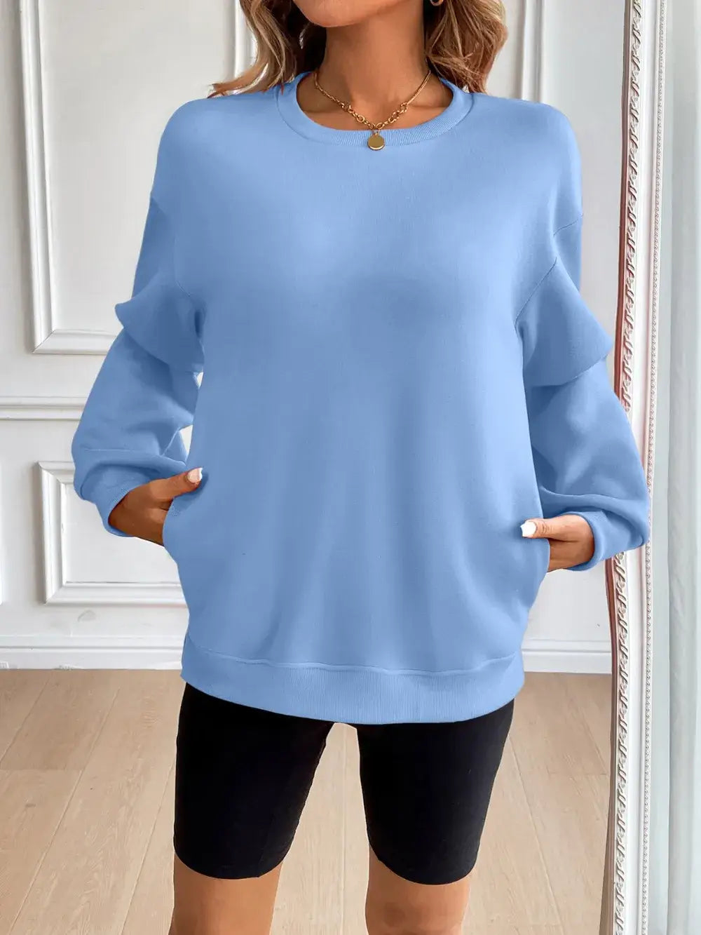 Ivy Lane light blue round neck long sleeve sweatshirt styled with pockets, paired with bike shorts.